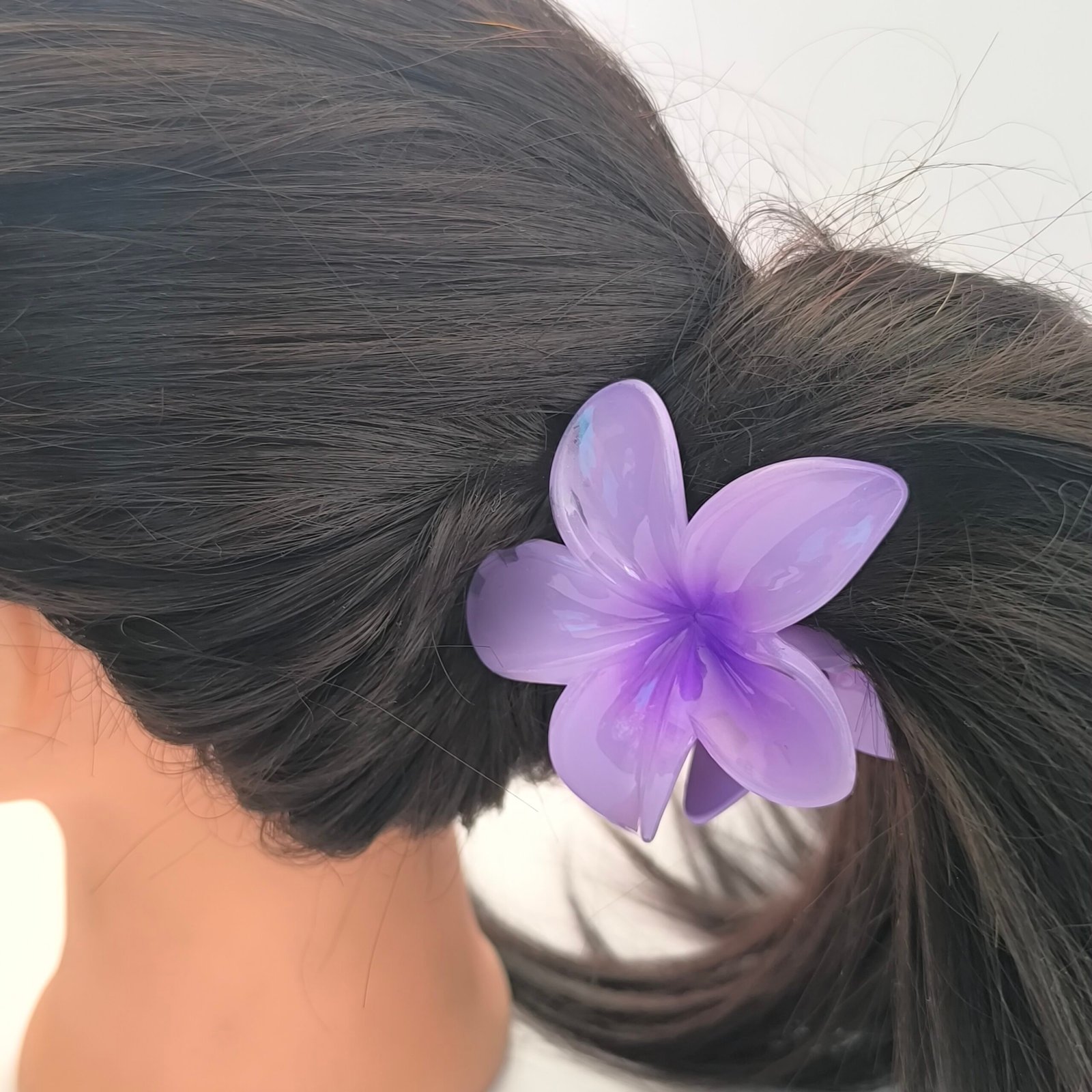 Pirana flor hawaiana lila puesta en cabello largo oscuro recogido mujer Bolivia