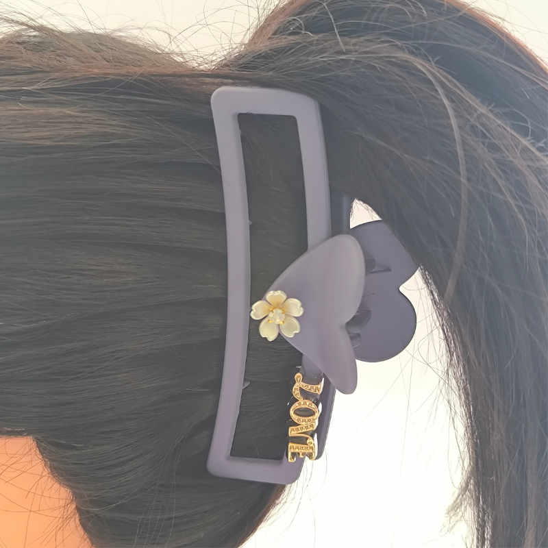 Vista lateral pirana rectangular Love gris mate sobre cabello largo oscuro abundante